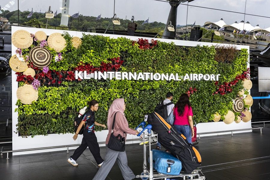 Passengers walk past a signage for the Kuala Lumpur International Airport (KLIA) in Sepang, Selangor, Malaysia, on 3 April 2024. (Richard Humphries/Bloomberg)