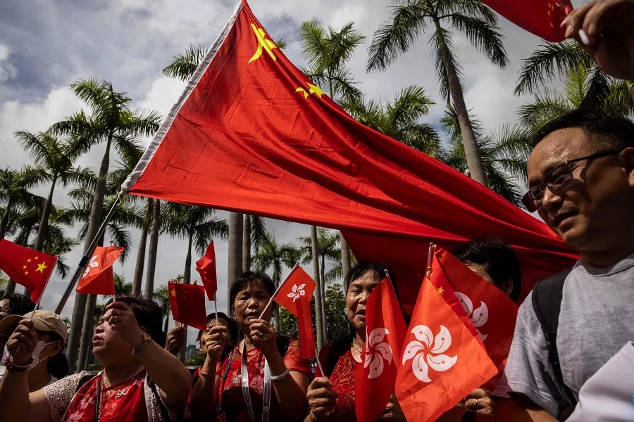 People wave the flags of Hong Kong and China on the Tsim Sha Tsui waterfront promenade in Hong Kong on 1 July 2023. (Isaac Lawrence/AFP)
