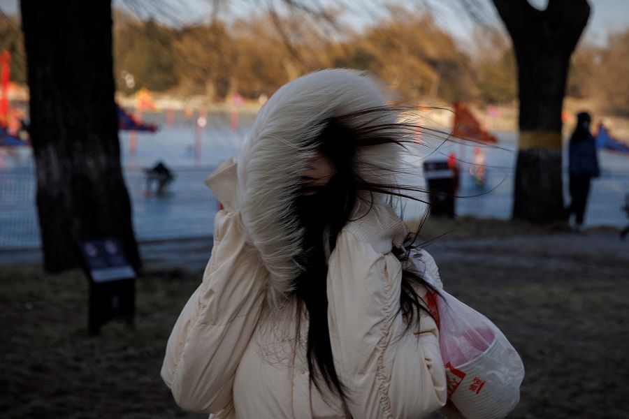A woman protects herself from the cold and the wind during Spring Festival celebrations in Beijing, China, 23 January 2023. (Thomas Peter/Reuters)