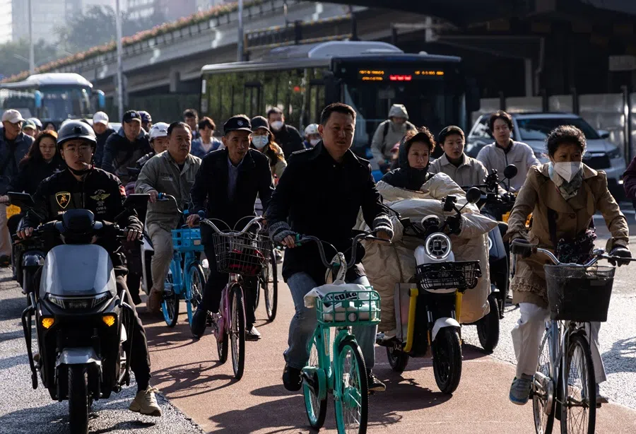 People ride bicycles and scooters during morning rush hour in Beijing, China, 13 October 2025. (Maxim Shemetov/Reuters)