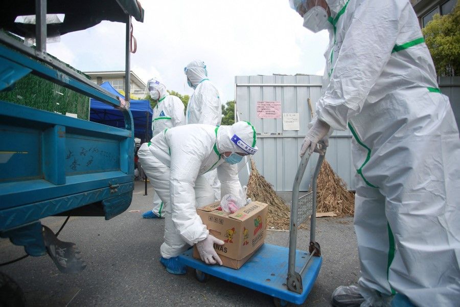 Volunteers and staff members wearing personal protective equipment (PPE) against the spread of Covid-19 coronavirus carry foods and daily necessities as they prepare to deliver for residents at a restricted residential area due to the virus in Yangzhou, in China's eastern Jiangsu province on 6 August 2021. (STR/AFP)