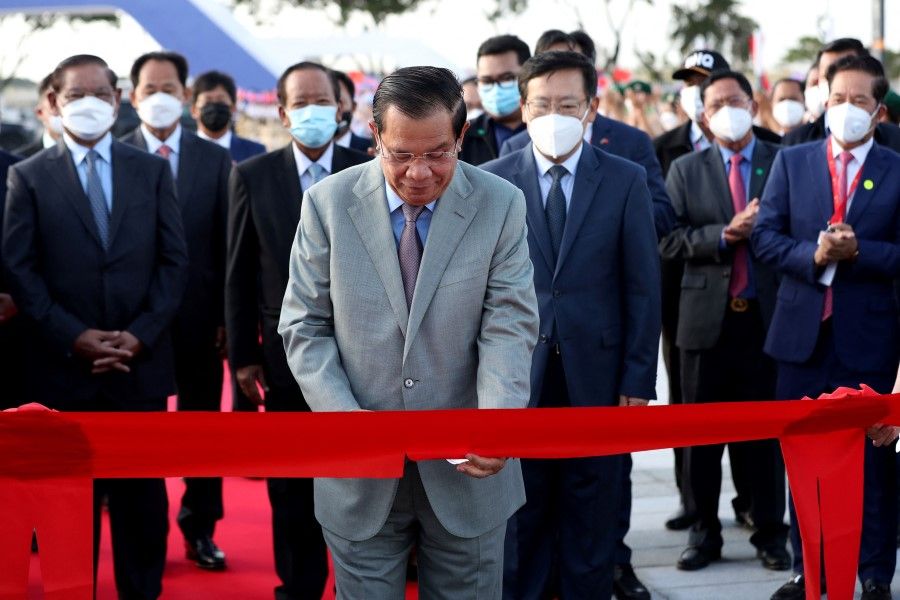 Cambodia's Prime Minister Hun Sen (centre) cuts a ceremonial ribbon as Chinese ambassador to Cambodia Wang Wentian (third from right) looks on during the opening ceremony of the Morodok Techo National Stadium, funded by China's grant aid under its Belt and Road Initiative, in Phnom Penh on 18 December 2021. (Lon Jadina/AFP)