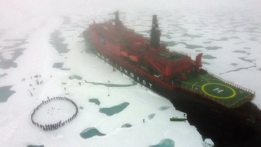 Russian teenagers who won a contest to travel aboard the Russian "50 Years of Victory" nuclear-powered icebreaker dance in circle at the North Pole next to the 160-metre (525-foot) ship on 18 August 2021. (Ekaterina Anisimova/AFP)