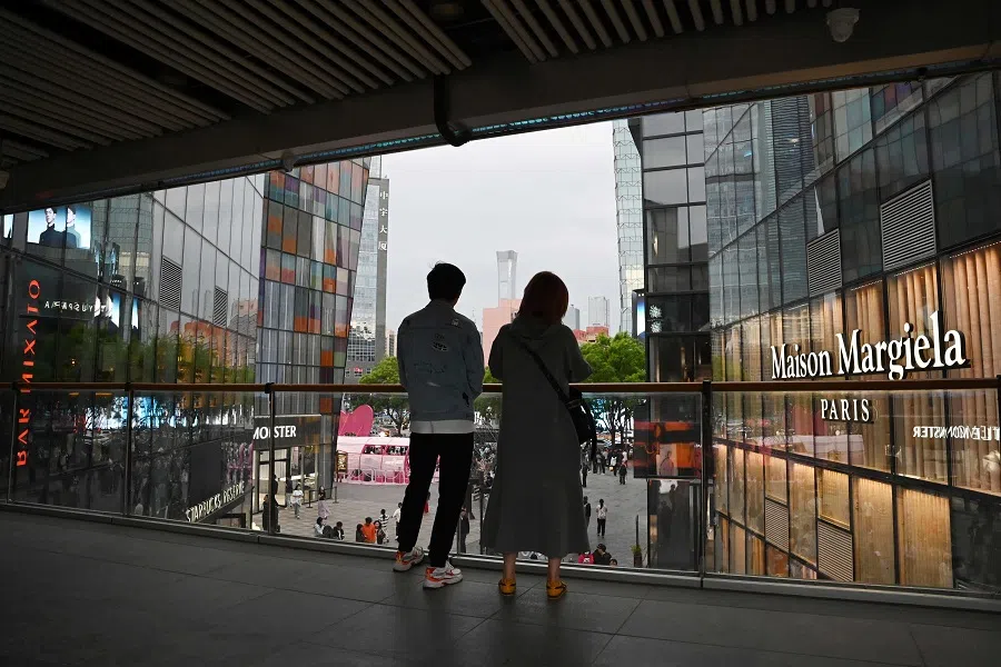 People look out from a shopping mall in Beijing, China, on 2 May 2025. (Greg Baker/AFP)