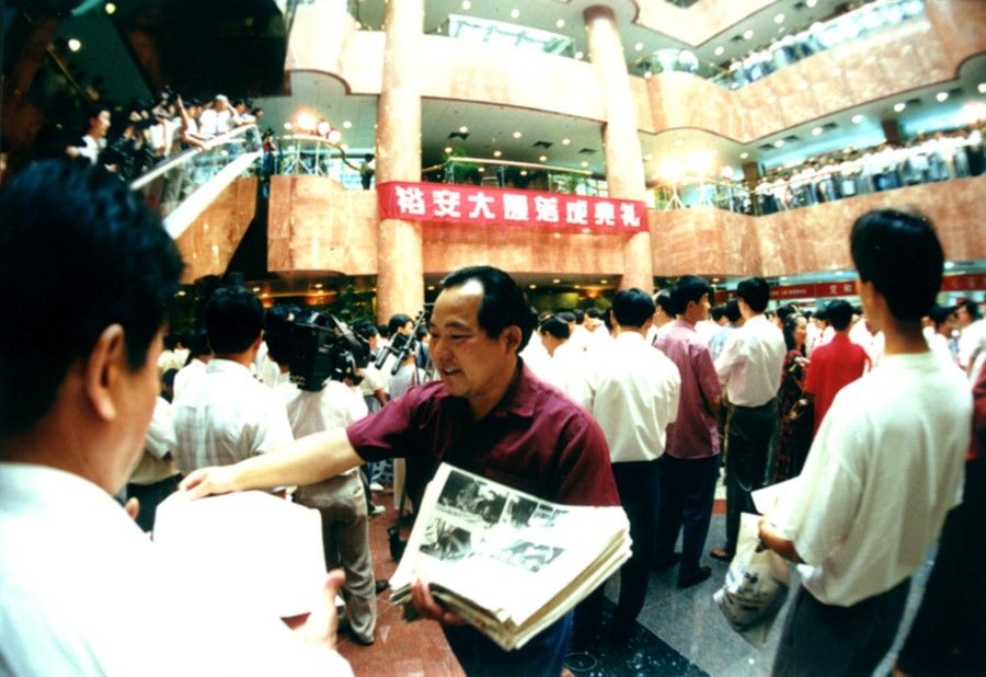 A crowd including the media at the opening of Yu'an Building, 1995. A staff member hands out flyers, hoping for an opportunity to make some money from this wave of economic development. The growth of the Yangtze River Delta provided opportunities and carried the hopes and dreams of many Chinese of making it big. In the photo, the enthusiasm for doing business is written on the man's face, a record of Chinese sentiment in those times.