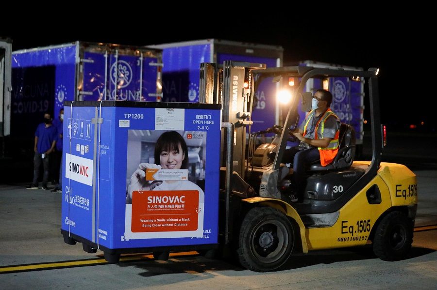 A worker transports a container carrying a batch of China's Sinovac Covid-19 vaccine at the Oscar Arnulfo Romero International Airport in San Luis Talpa, El Salvador, 18 May 2021. (Jose Cabezas/Reuters)
