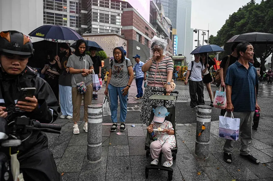 People wait for the traffic lights outside a shopping mall in Guangzhou, Guangdong province, China, on 18 April 2025. (Jade Gao/AFP)