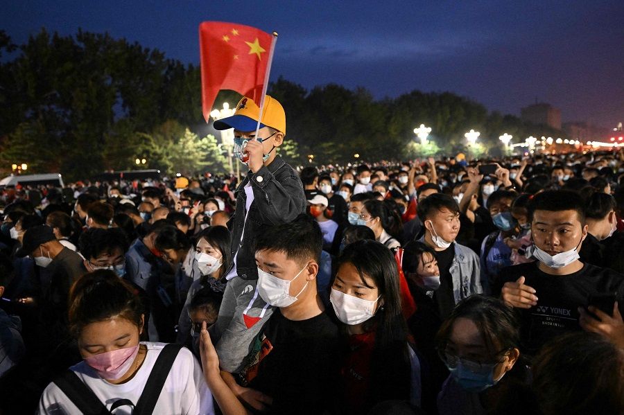 A child waves the Chinese national flag as people gather near Tiananmen Square for the flag-raising ceremony on China's National Day in Beijing, China, on 1 October 2022. (Noel Celis/AFP)
