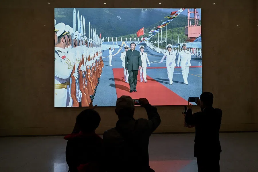 This picture taken during a media tour organised by the PLAN to mark its 75th founding anniversary, shows people looking at a picture of Chinese President Xi Jinping inspecting the Chinese Navy Shandong aircraft carrier, at the PLA Naval Museum in Qingdao, China’s Shandong province, on 23 April 2024. (Wang Zhao/AFP)