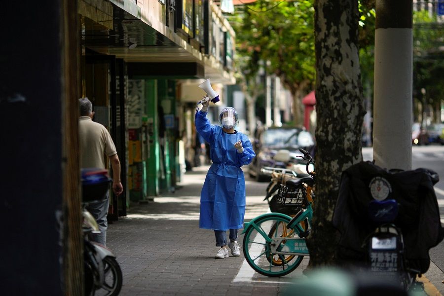 A worker in a protective suit speaks through a megaphone as she directs residents of the buildings to go for nucleic acid testing on a street, following the Covid-19 outbreak, in Shanghai, China, 25 September 2022. (Aly Song/Reuters)