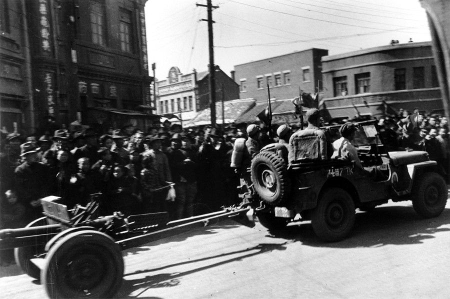 In April 1946, troops from the New 1st Army go past the podium in a US-style jeep pulling a light cannon.