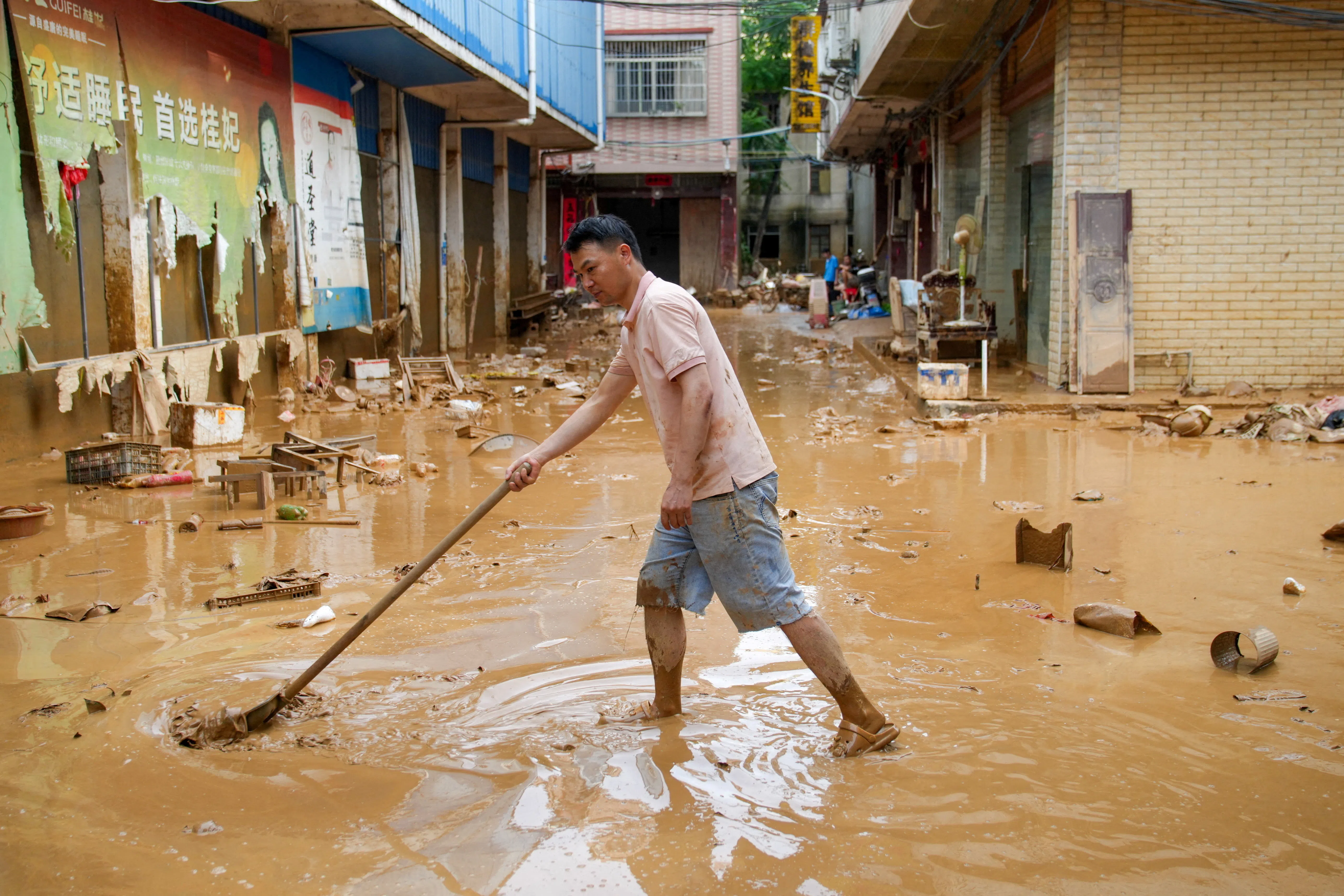 A man clears mud after heavy rainfall brought by Typhoon Maysak in flooded Sanli town in Guigang, Guangxi Zhuang Autonomous Region, China, 9 July 2026.