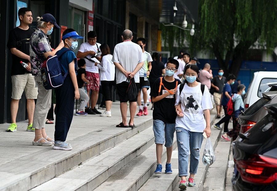 This picture taken on 28 July 2021 shows students walking with their guardians after attending private after-school education in Haidan district of Beijing, China. (Noel Celis/AFP)