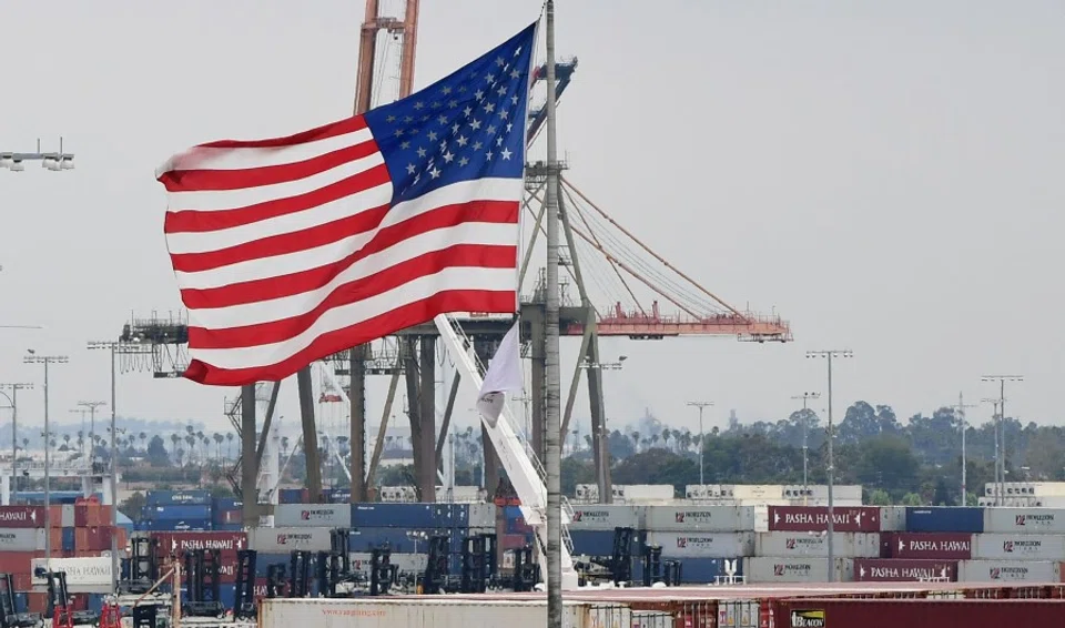 In this file photo the US flag flies in the foreground as containers are seen at the Port of Los Angeles on 18 June 2019 in San Pedro, California. Spending by American consumers and record-high imports as the global economy reopened drove the US trade gap to a new all-time high in March, the Commerce Department reported on 4 May 2021. The trade deficit rose 5.6% to US$74.4 billion, the highest ever recorded and mostly attributable to trade with China. (Frederic J. Brown/AFP)