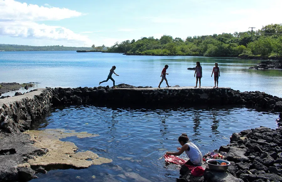 A woman washes clothes as children play near the water on the island of SavaiÕi, Samoa, 16 July 2019. (Jonathan Barrett/File Photo/Reuters)