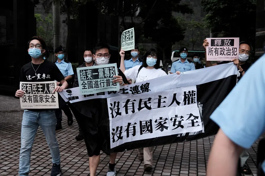 Four Hong Kong pro-democracy activists holding a banner and placards reading "No Democracy and Human Rights, No National Security" and "Free All Political Prisoners" march in Hong Kong on 15 April 2021 to protest against the city's first National Security Education Day. (Yan Zhao/AFP)