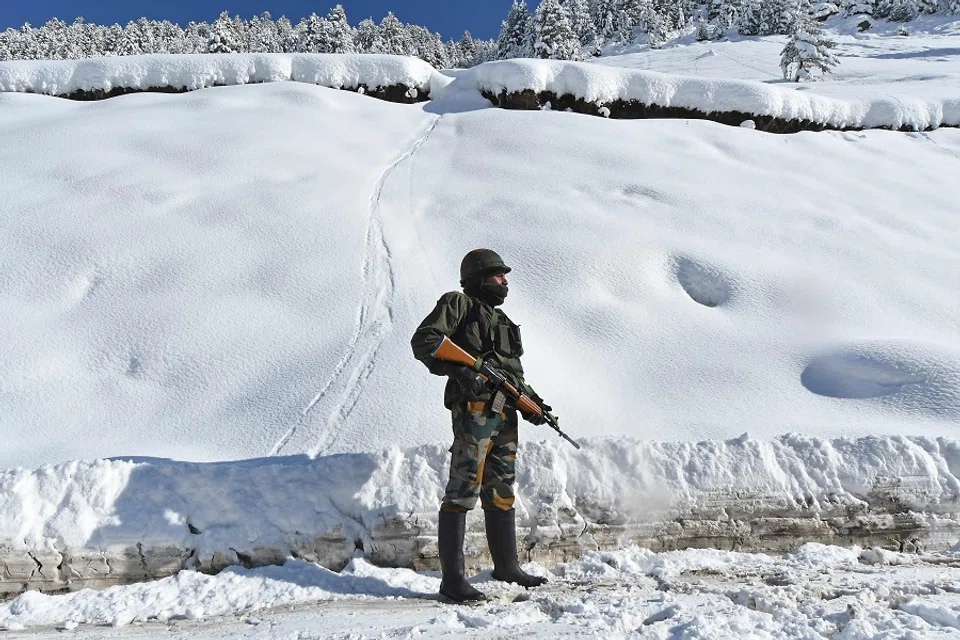 Indian army soldier stands on a snow-covered road near Zojila mountain pass that connects Srinagar to the union territory of Ladakh, bordering China, 28 February 2021. (Tauseef Mustafa/AFP)