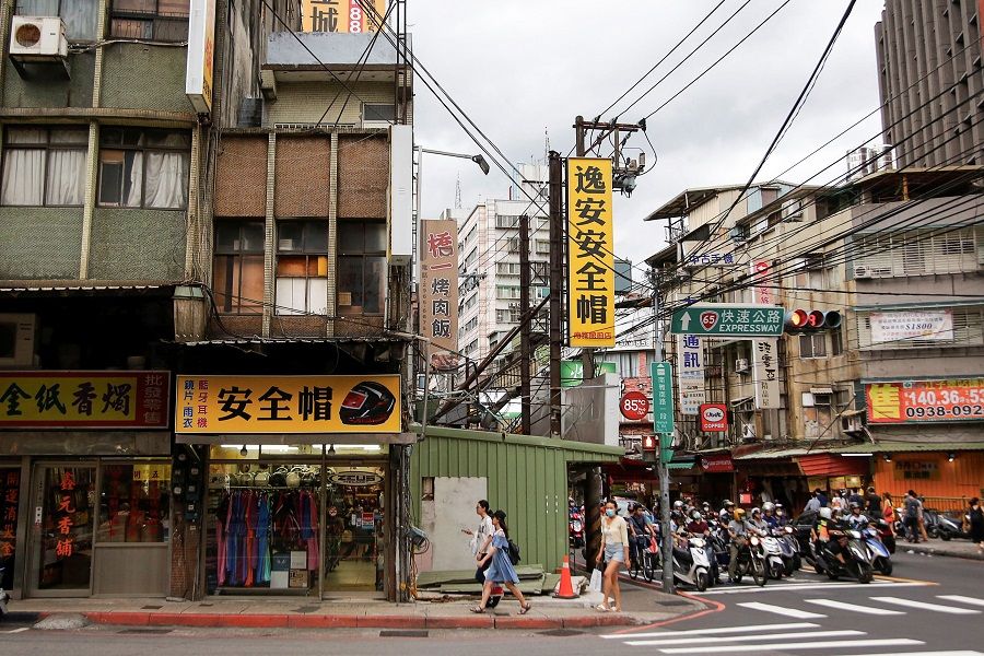 People wearing face masks walk by shops in Taipei, Taiwan, 8 July 2020. (Ann Wang/Reuters)