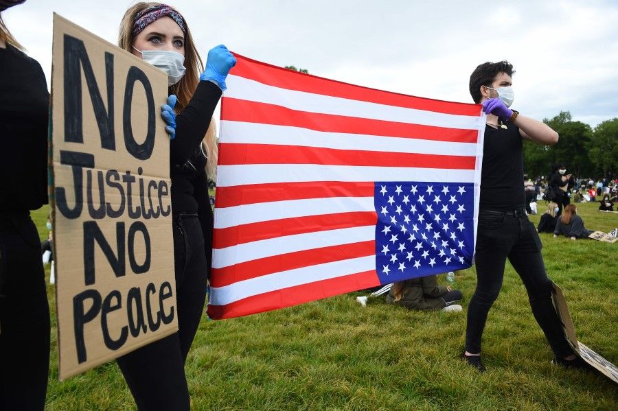 Protesters hold up an upside-down US flag at a demonstration in Edinburgh on June 7, 2020, organised to show solidarity with the Black Lives Matter movement. (Andy Buchanan/AFP)