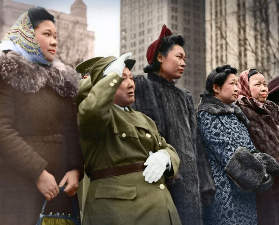 Amid the crowd, a woman in military uniform and white gloves salutes Madame Chiang's entourage, 1943.