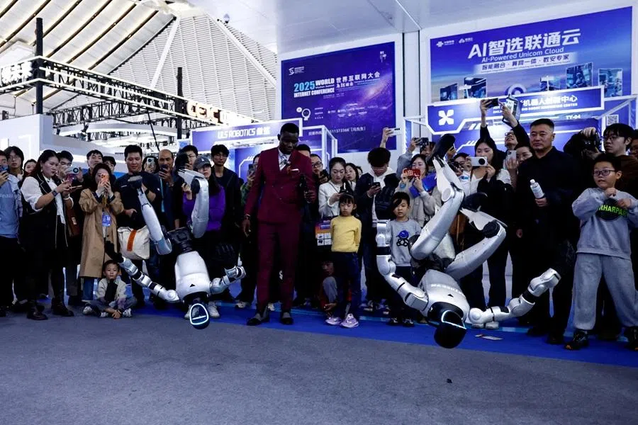 Visitors watch Unitree humanoid robots performing a backflip at the expo of the World Internet Conference in Wuzhen town of Tongxiang city, Zhejiang province, China, 8 November 2025. (Tingshu Wang/Reuters)
