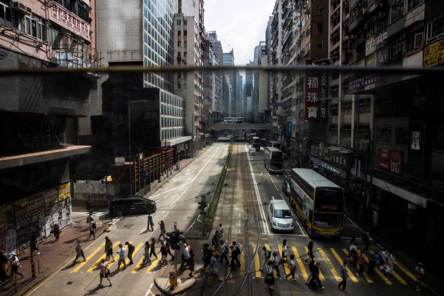 Pedestrians cross the street in the Causeway Bay district of Hong Kong on 19 May 2023. (Isaac Lawrence/AFP)