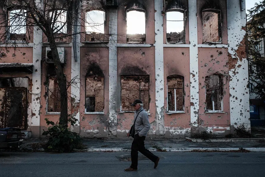 A pedestrian walks in front of a destroyed building in Izyum, Kharkiv region, Ukraine, on 25 September 2022, amid the Russian invasion of Ukraine. (Yasuyoshi Chiba/AFP)