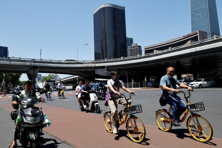 People ride bikes and scooters on a street at Beijing's Central Business District, in Beijing, China, on 21 June 2023. (Tingshu Wang/Reuters)