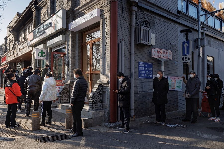 People line up outside a pharmacy to buy products in Beijing, China, 8 December 2022. (Thomas Peter/Reuters)