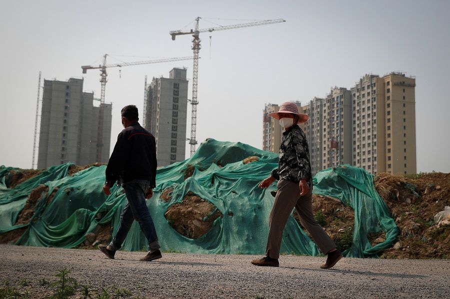 People wear protective masks as they walk past a construction site for residential housing amid the spread of the Covid-19 coronavirus in Beijing, China, on 30 April 2020. (Thomas Peter/Reuters)