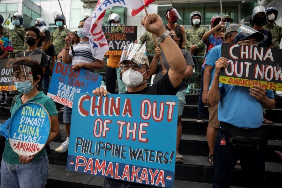 Activists stage a protest outside the Chinese consulate, guarded by Philippine police, on the fifth anniversary of an international arbitral court ruling invalidating Beijing's historical claims over the waters of the South China Sea, in Makati City, Philippines, 12 July 2021. (Eloisa Lopez/Reuters)