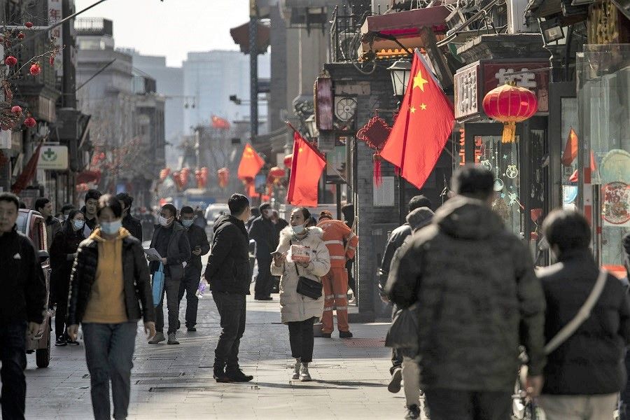 Pedestrians pass Chinese flags in Beijing, China, on 3 March 2022. (Qilai Shen/Bloomberg)