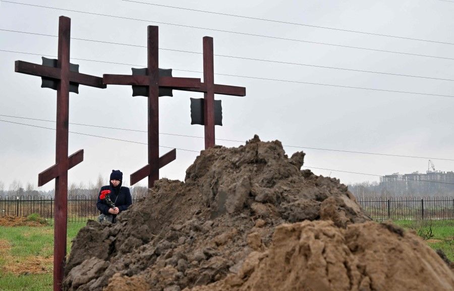 A mourner attends the funeral of a family of three in Bucha, on the outskirts of Kyiv on 22 April 2022, who were reportedly killed by Russian troops. (Sergei Supinsky/AFP)