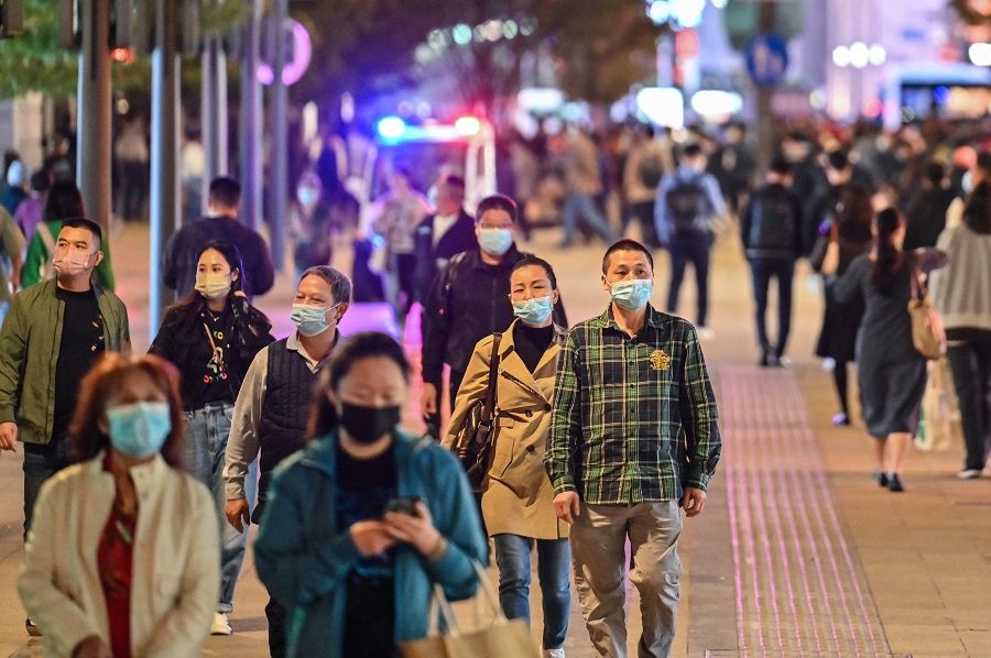 People walk along a pedestrian street surrounded by shops and shopping malls in Shanghai, China, on 24 October 2022. (Hector Retamal/AFP)