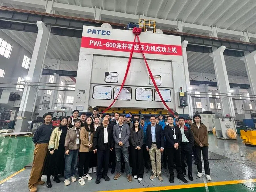 The photo shows a precision press machine designed by PATEC for a Chinese client. Michael Wee stands in the front row, fifth from left.