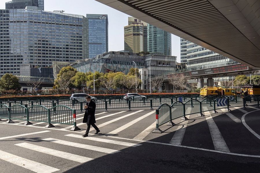 A pedestrian crosses a near-empty road in Shanghai, China, on 23 March 2022. (Qilai Shen/Bloomberg)