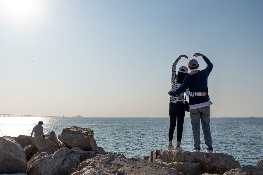 This picture taken on 14 November 2021 shows visitors posing for a photo at a scenic spot in Hong Kong. (Bertha Wang/AFP)