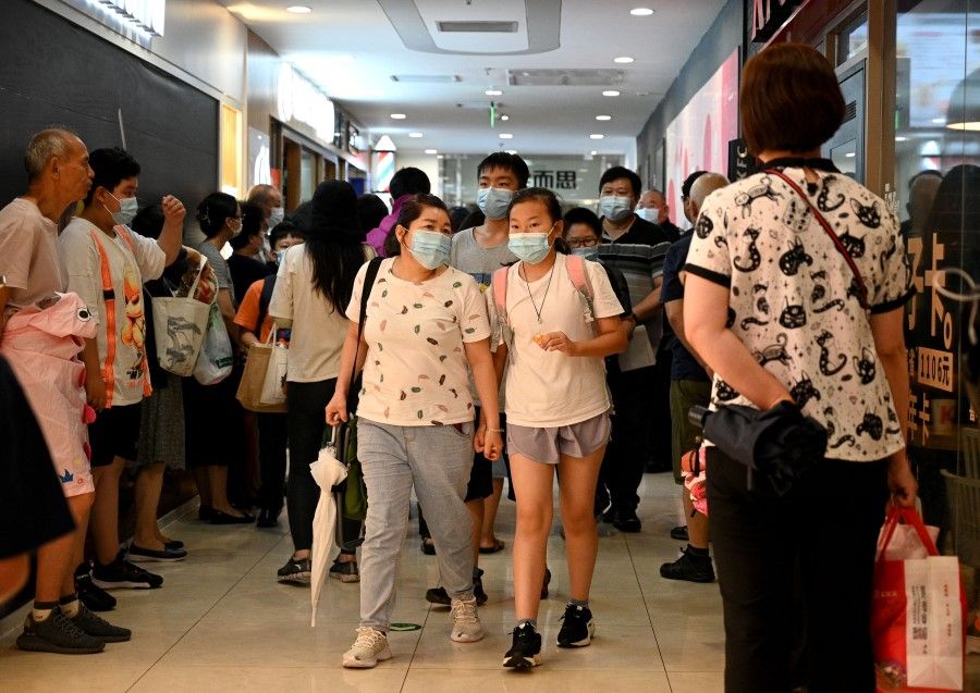 This picture taken on 29 July 2021 shows students and parents walking after attending a private after-school education in Haidan district of Beijing. (Noel Celis/AFP)