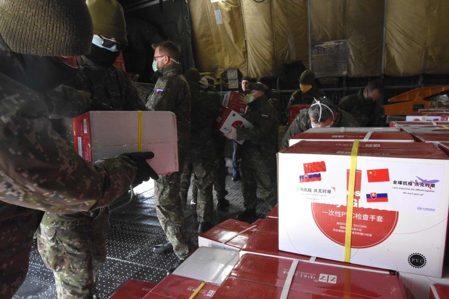 Slovak military personnel unload boxes with a sheet reading "Let's overcome difficulties together, don't give up" inside an Ukrainian cargo plane An-12 Ruslan shortly after it has arrived from China, loaded with 74 tons of face masks, respirators and test kits at M.R. Stefanilk airport in Bratislava, Slovakia on March 25, 2020. (AFP)