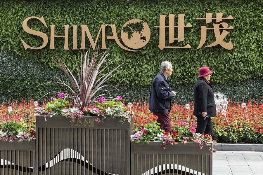 An elderly couple walks past a sign in front of Shimao Tower in Shanghai, China, on 8 January 2022. (Qilai Shen/Bloomberg)