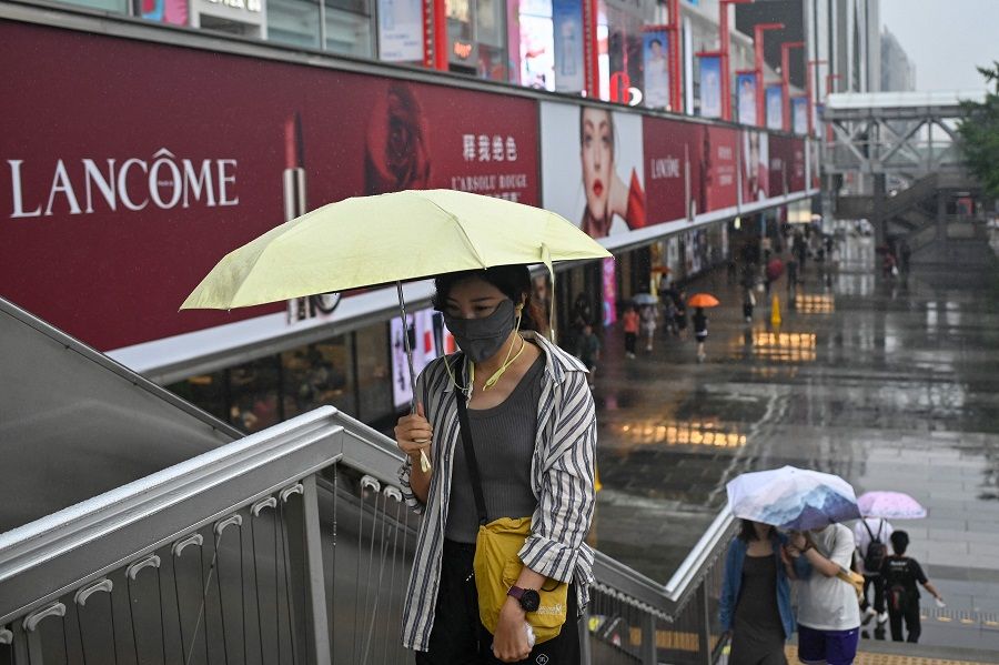 People walk past a shopping mall in Beijing, China, on 13 July 2023. (Wang Zhao/AFP)