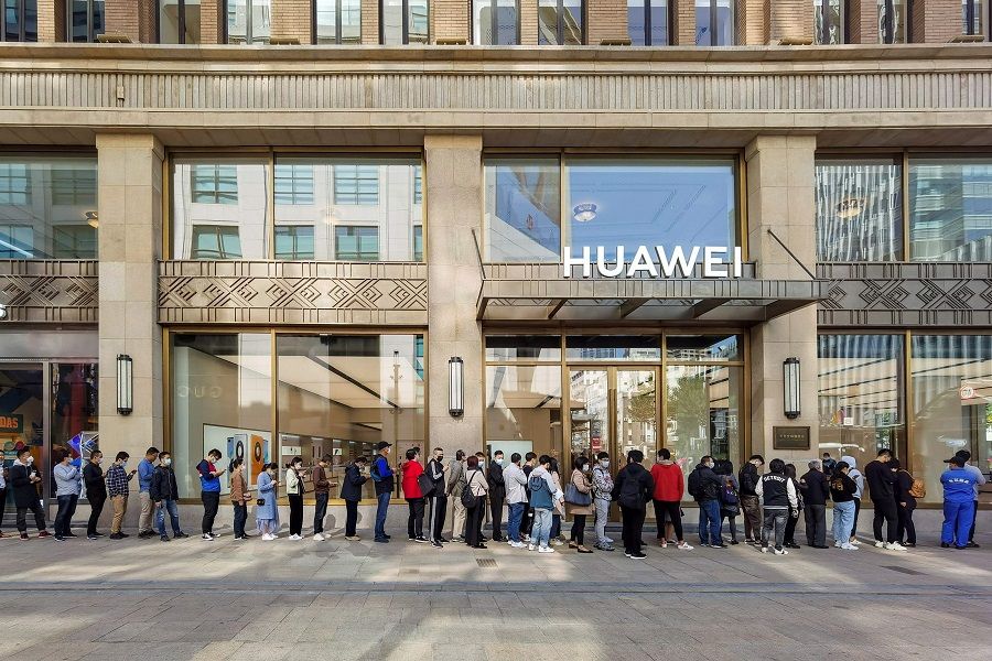 People wearing masks wait in line in front of Huawei's flagship store for pre-sales of the newly launched Huawei Mate 40 mobile phone series in Shanghai on 23 October 2020. (STR/AFP)