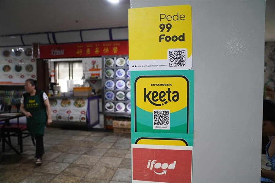 Posters for 99Food, Keeta and iFood line the entrance of a Chinese fast-food shop at São Paulo’s Rua 25 de Março wholesale market, on 22 November 2025. (Zhang Ruixue/Caixin)