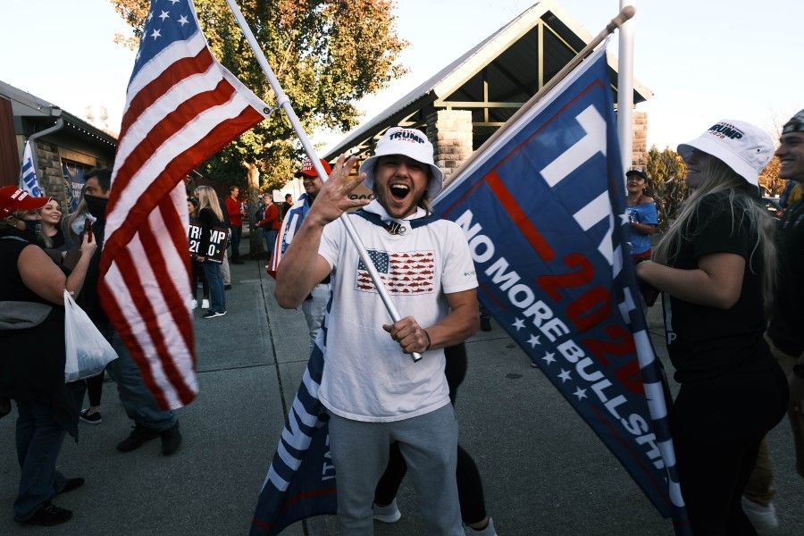 Supporters of President Donald Trump wave flags and hold signs at Skylands Stadium during an election rally on 14 October 2020 in Augusta, New Jersey. (Spencer Platt/AFP)