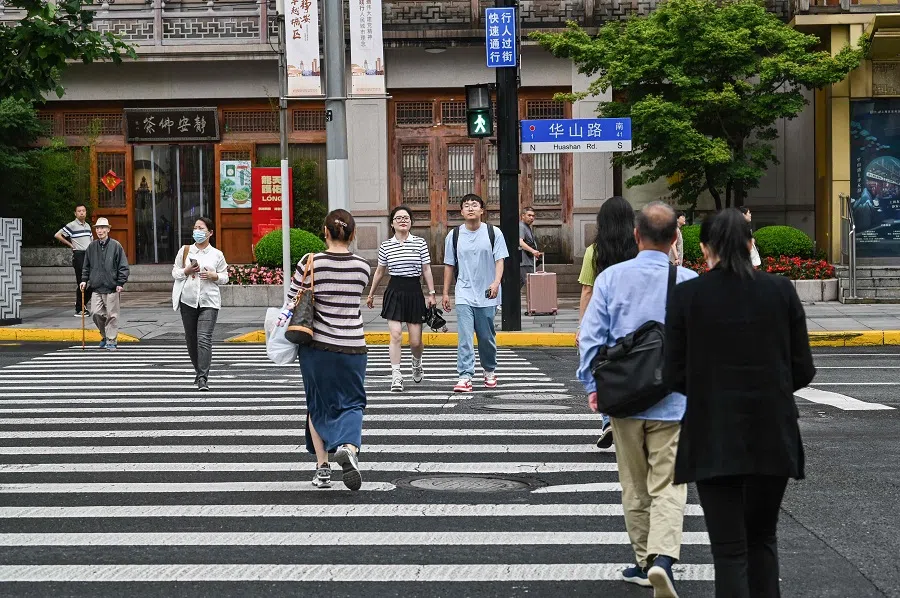 People cross a street at the Jing’an district in Shanghai on 31 May 2024. 