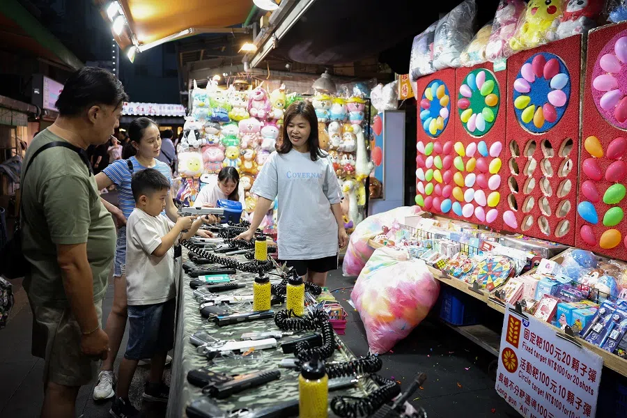 A family plays a shooting game at a night market in Taipei, Taiwan, on 19 May 2024. (Ann Wang/Reuters)