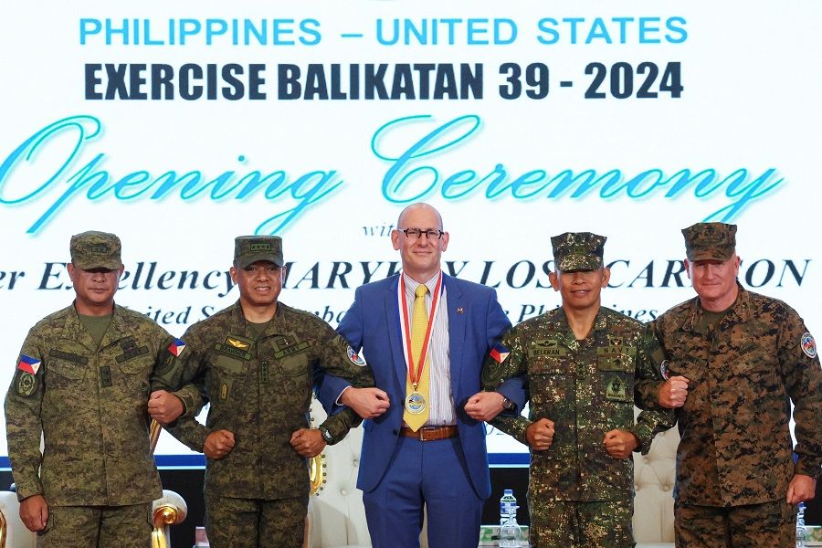 Philippines exercise director Major General Marvin Licudine, Philippine Army Chief of Staff Romeo Brawner Jr, US embassy representative Robert Ewing, Philippine Army Deputy Chief of Staff for Education, Training and Doctrine Major General Noel Beleran, and US exercise director Lieutenant-General William Jurney link arms during the opening ceremony of the annual Philippines-US joint military exercises or Balikatan, at the Armed Forces of the Philippines headquarters, in Quezon City, Metro Manila, Philippines, on 22 April 2024. (Eloisa Lopez/Reuters)