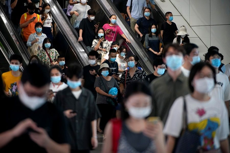 People wearing protective masks ride escalators inside a subway station in Shanghai, China, 5 August 2021. (Aly Song/Reuters)