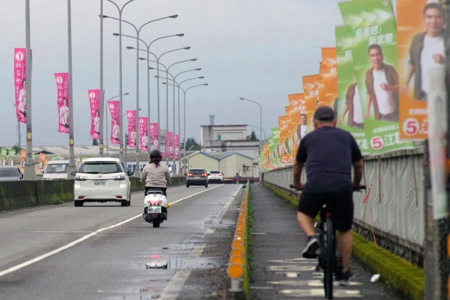 This picture taken on 22 November 2022 shows commuters riding past election campaign flags on a bridge in Yilan county. (Sam Yeh/AFP)