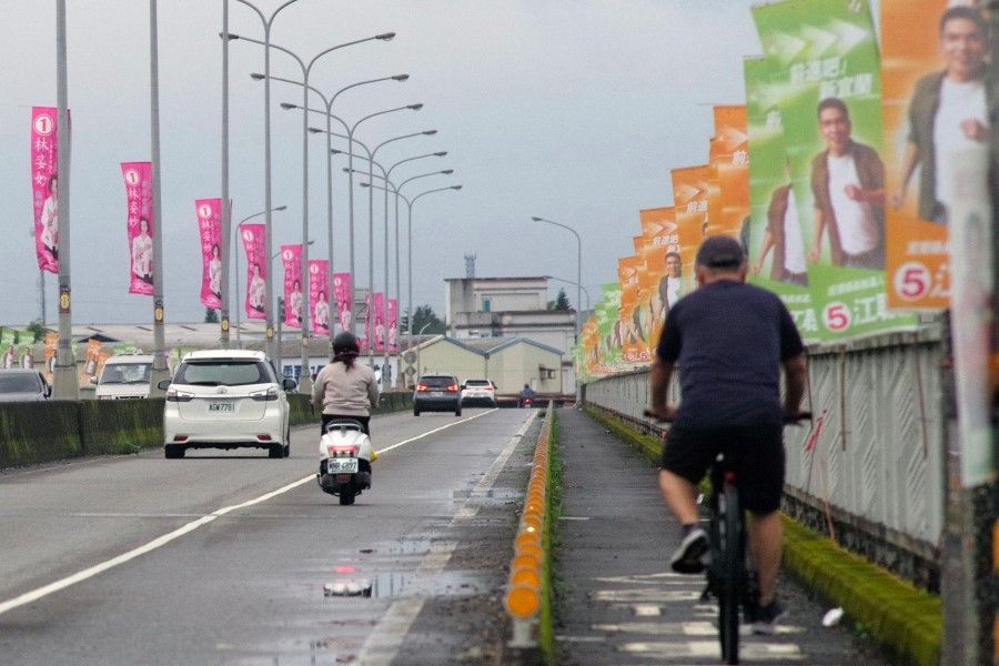 This picture taken on 22 November 2022 shows commuters riding past election campaign flags on a bridge in Yilan county. (Sam Yeh/AFP)